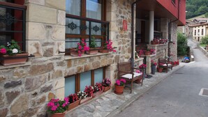 Un edificio de piedra con varias ventanas y macetas con flores en la planta baja.