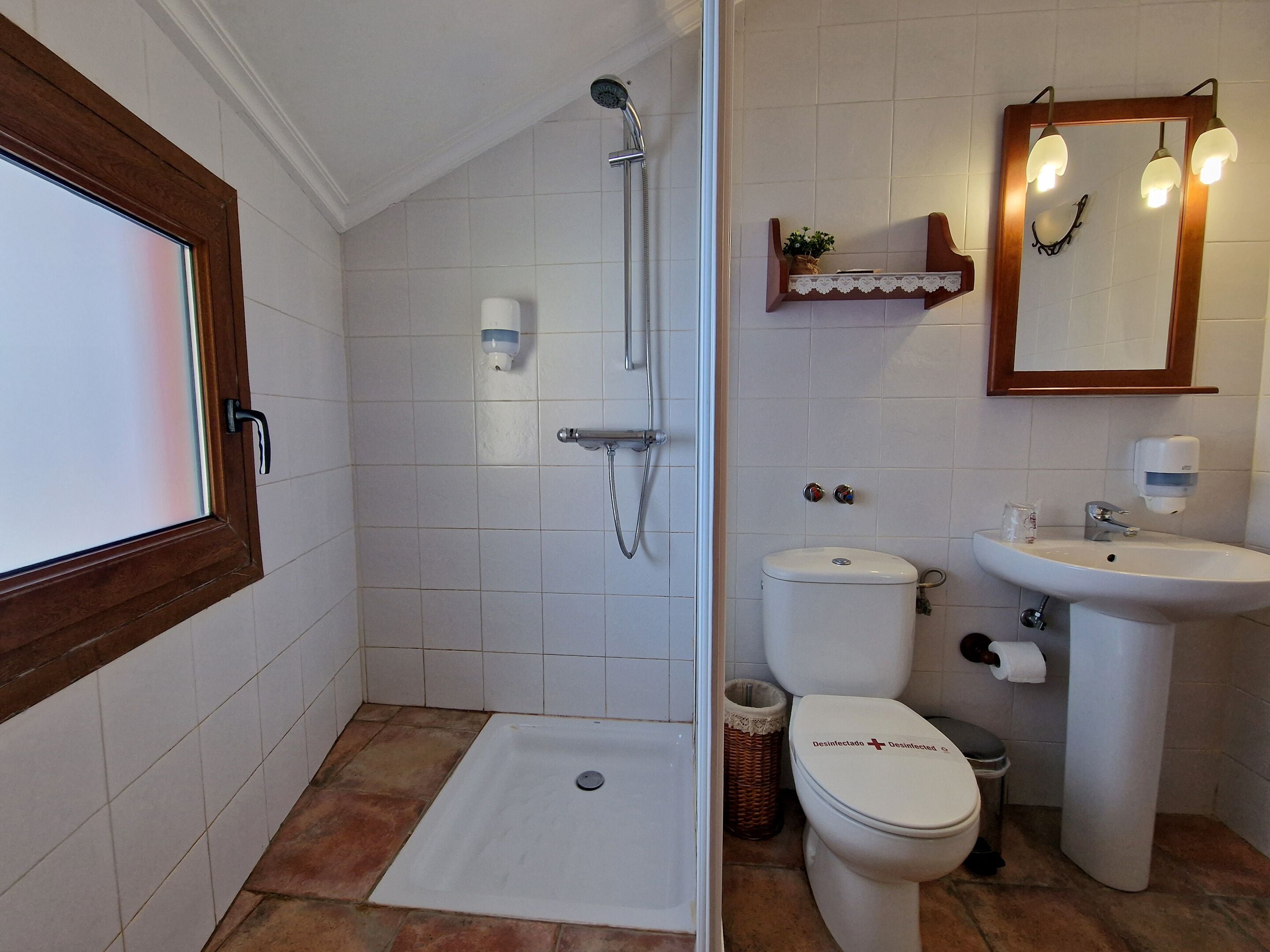 A bathroom with a shower, toilet, sink, and a mirror with lights.
