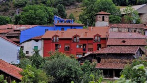 Un pueblo con techos rojos tradicionales, un edificio azul destacado y una montaña al fondo.
