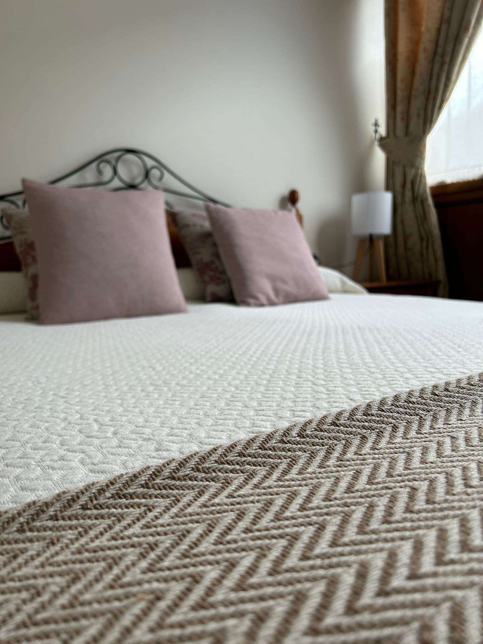 A bed with a patterned bedspread and two pillows.