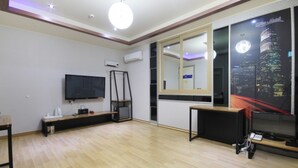 A modern living room with a flat-screen TV, wooden flooring, a large mirror, and a cityscape mural on the wall. - Blue Motel (Gwangju)