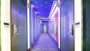 A hallway with a patterned carpet, doors with a blue sign, and a ceiling with a starry design. - Blue Motel (Gwangju)