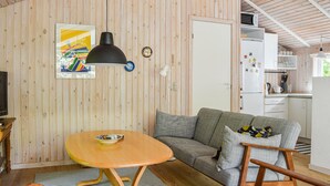 Un espacio de sala acogedor con una mesa de madera, un sofá gris y un televisor.