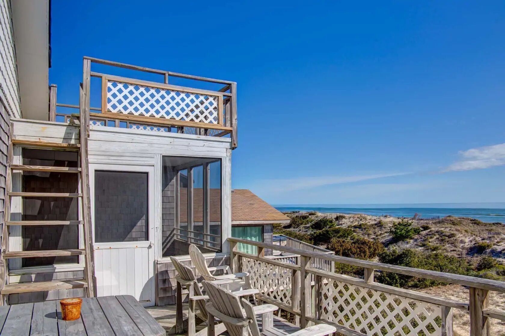 Une terrasse en bois offrant une vue sur la plage et l’océan.