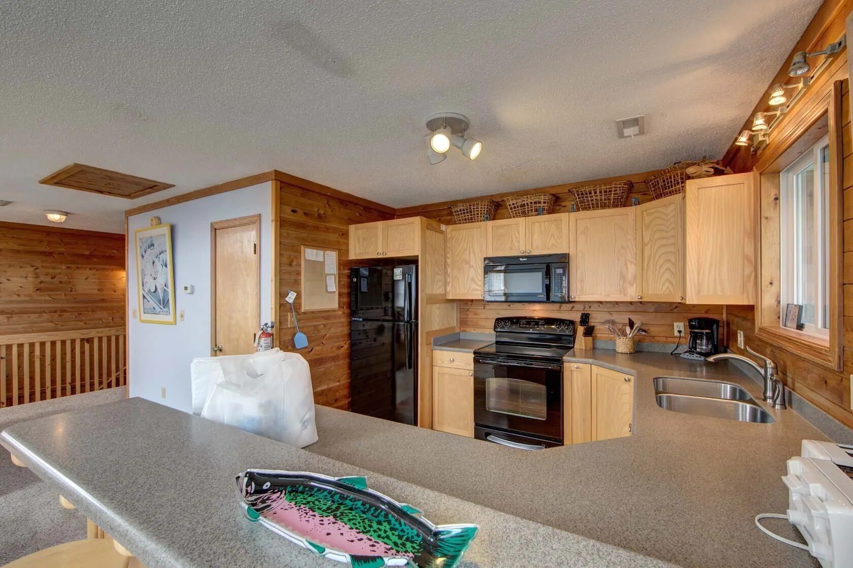 A modern kitchen with wooden cabinets, a black refrigerator, a microwave, and a stove.