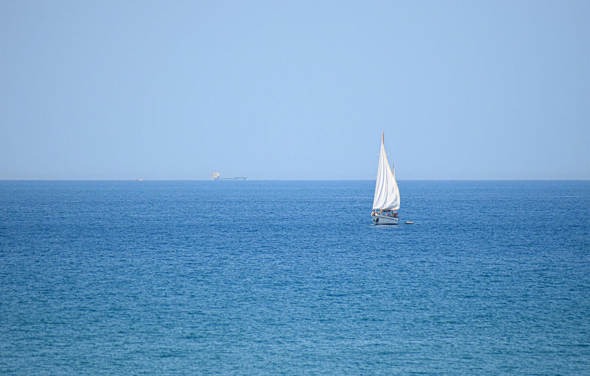 Un voilier sur une mer calme, avec un horizon dégagé.