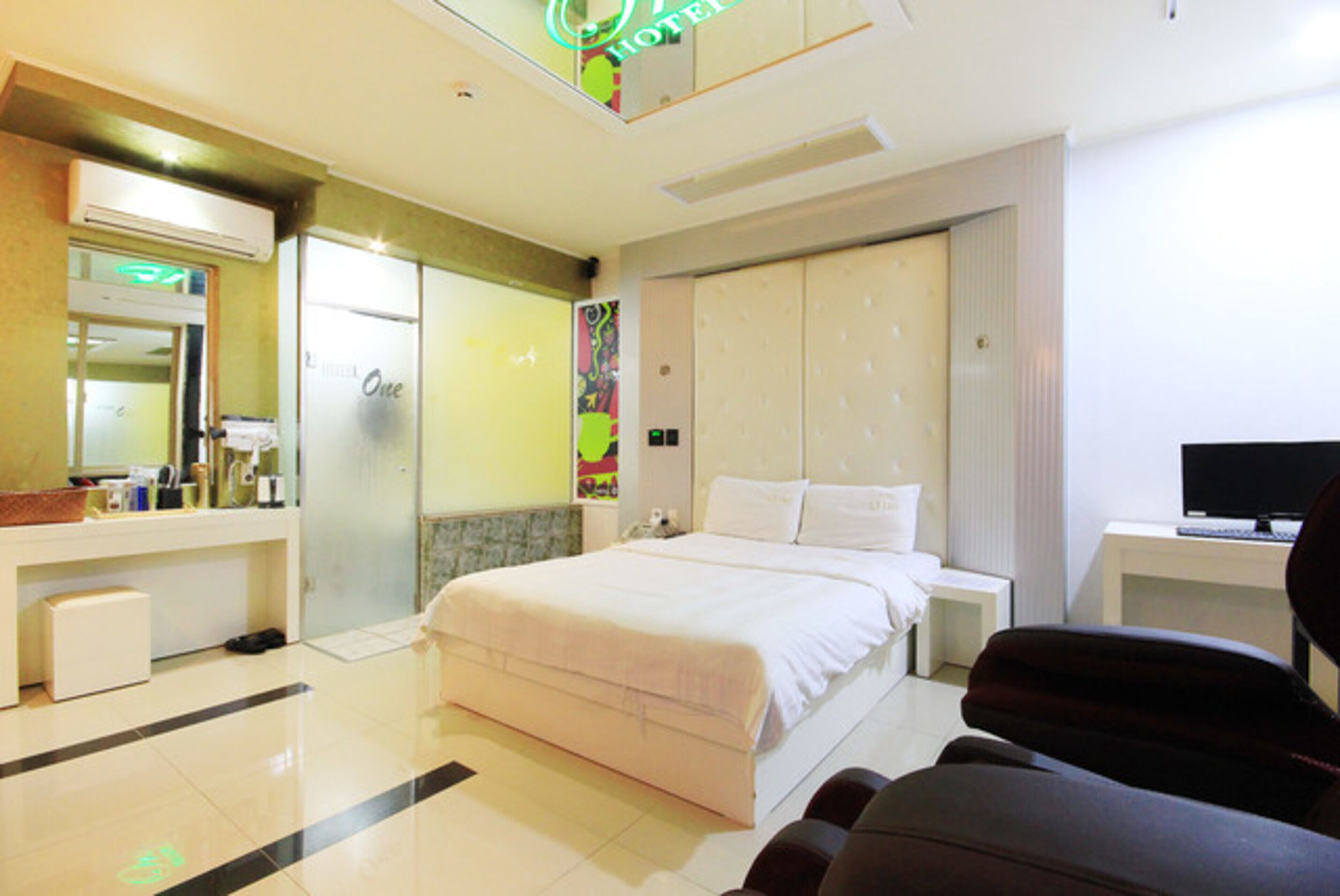 A hotel room with a bed, a desk, a chair, a mirror, and a wardrobe.