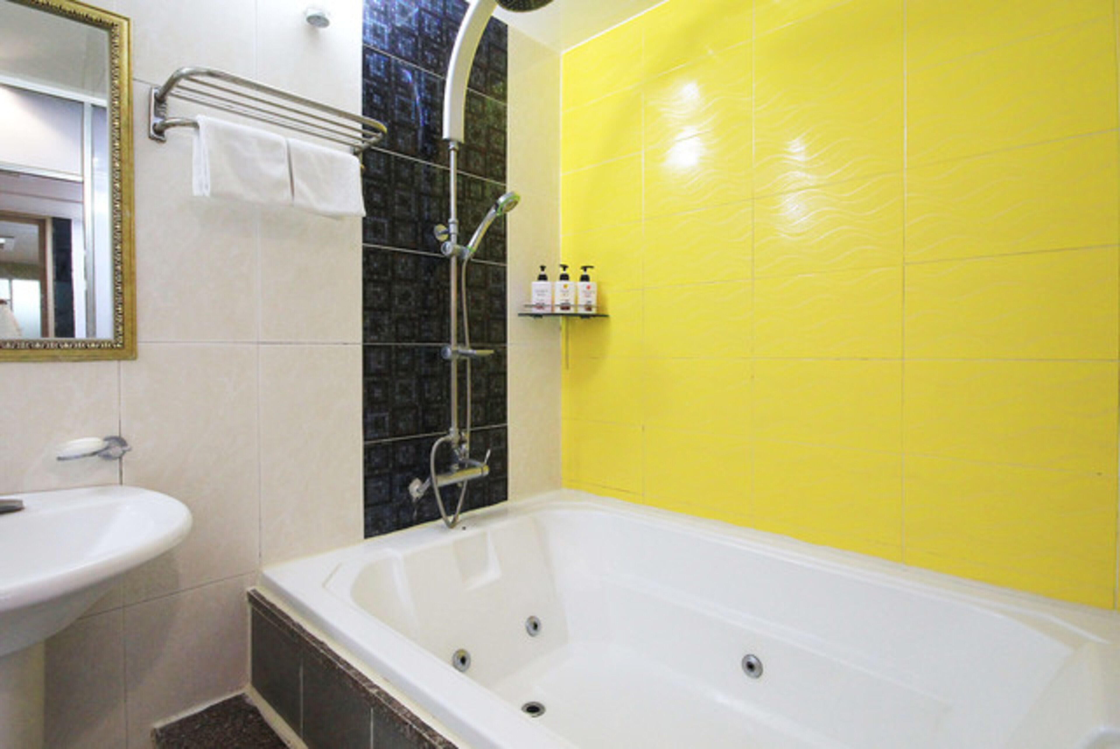 A bathroom with a white bathtub, a sink, a mirror, and a shelf with toiletries.