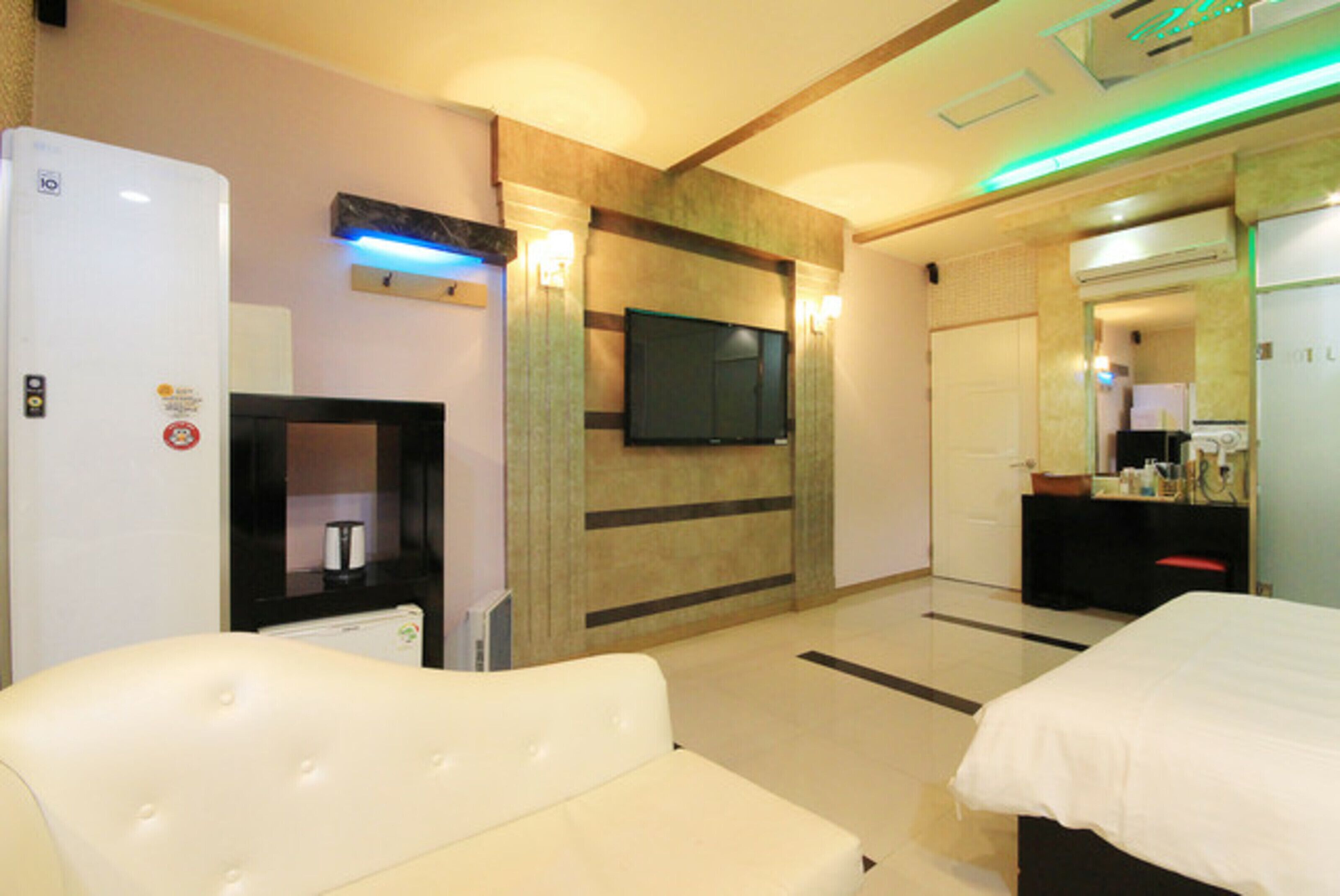 Una habitación de hotel con televisión de pantalla plana, minibar, sofá y cama.