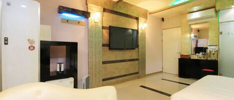 Una habitación de hotel con televisión de pantalla plana, minibar, sofá y cama.