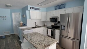 A kitchen with white cabinets, stainless steel appliances, and a granite countertop. - Oceanfront Complex with Ocean Views. (Ocean Isle Beach)