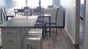 A kitchen with a central island, white cabinetry, and a wooden floor. - Oceanfront Complex with Ocean Views. (Ocean Isle Beach)