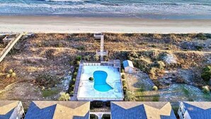 An aerial view of a beachside property with a swimming pool, a wooden deck, and a beach in the background. - Oceanfront Complex with Ocean Views. (Ocean Isle Beach)