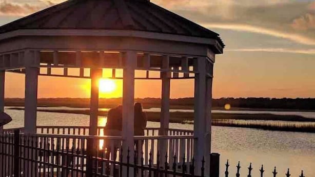 A gazebo with a metal roof and white walls, situated near a body of water during sunset. - Oceanfront Complex with Ocean Views. (Ocean Isle Beach)