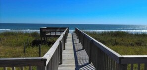 Une promenade en bois menant à une plage avec vue sur l’océan.