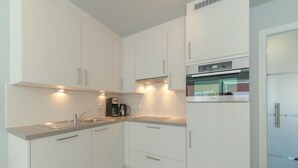 A modern kitchen with white cabinets, a built-in oven, and a coffee maker. - Seaside 101 with parking by Interhome (Bredene)