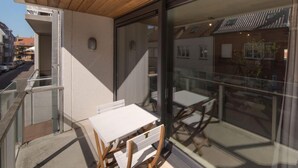 A balcony with a wooden ceiling, glass doors, and a table with chairs. - Seaside 101 with parking by Interhome (Bredene)