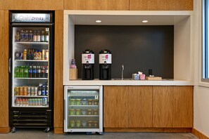 A self-service beverage station with a refrigerator and a freezer, stocked with various drinks and frozen foods. - Aloft by Marriott Mooresville (Mooresville)
