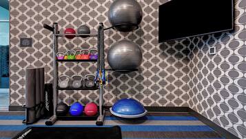 A gym with exercise equipment, a black mat, and a patterned wall.