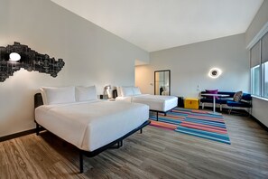 A modern hotel room with two beds, a desk, a chair, a colorful striped rug, and a unique wall light fixture. - Aloft by Marriott Mooresville (Mooresville)