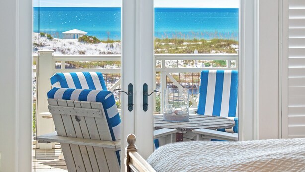 Ein Schlafzimmer mit Meerblick, ein Bett, ein Sessel und eine Kandelaber.