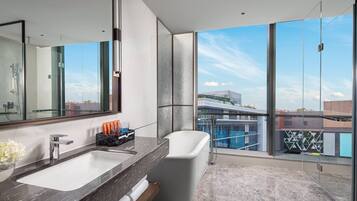 A modern bathroom with a large mirror, a white bathtub, and a marble sink.