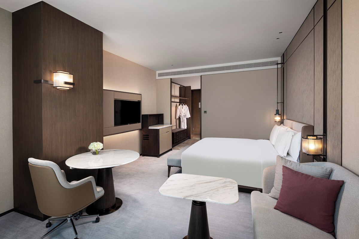 Una habitación de hotel con cama, sofá, escritorio, silla y televisión.