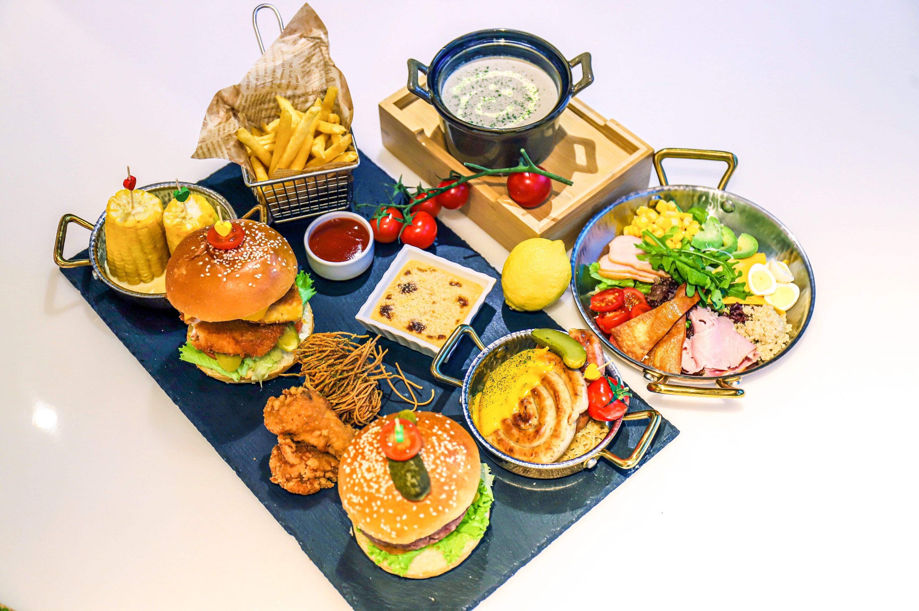 A variety of food items including burgers, fries, and a salad on a table.
