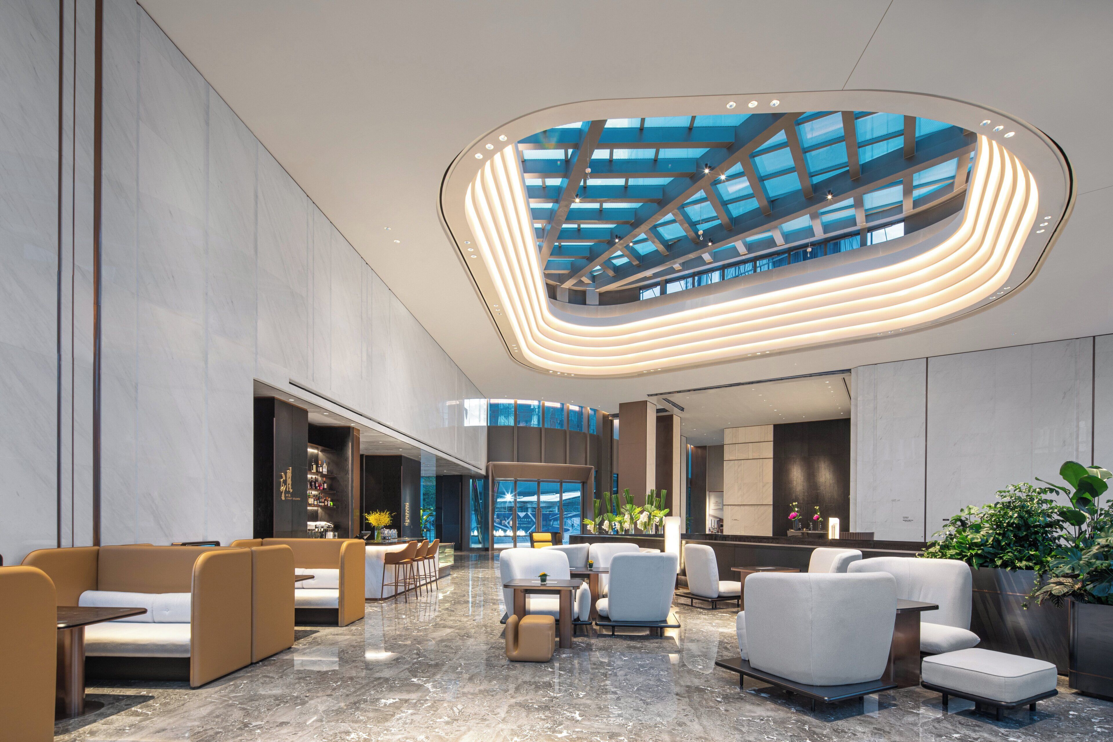 A modern lobby with seating areas, a bar, and a large skylight.