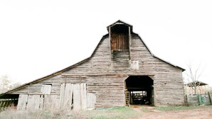 A large, rustic barn with a steep roof and a central door. - Historic 1880 Farmhouse with Modern Southern Charm (Casar)