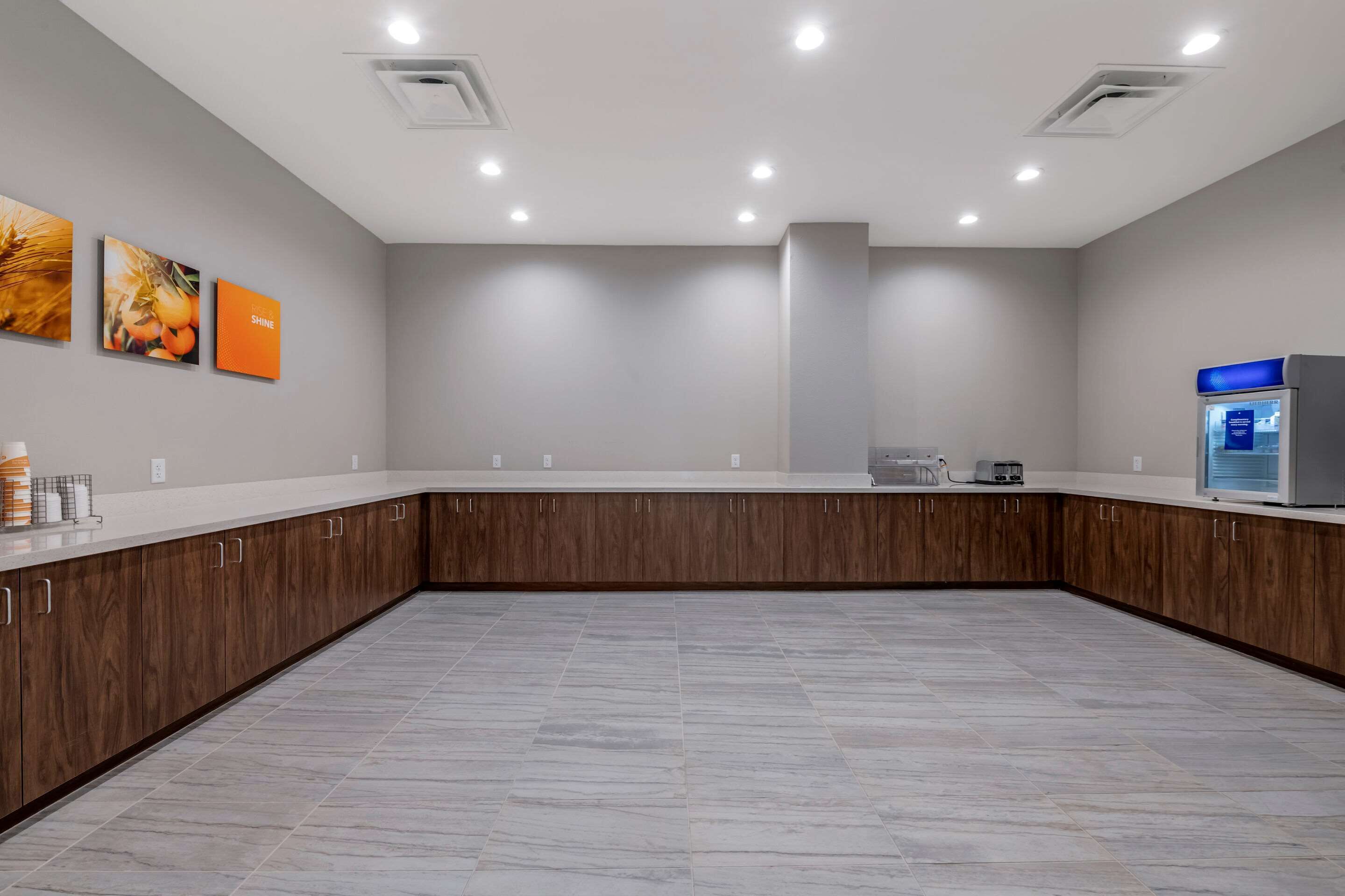 A spacious kitchen with a marble floor, wooden cabinets, and a built-in oven.