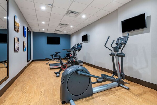 A gym with cardio equipment, a TV, and artwork on the walls. - Comfort Suites Gainesville near University (Gainesville)