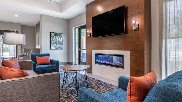 A modern living room with a fireplace, comfortable seating, a flat-screen TV, and a large window.