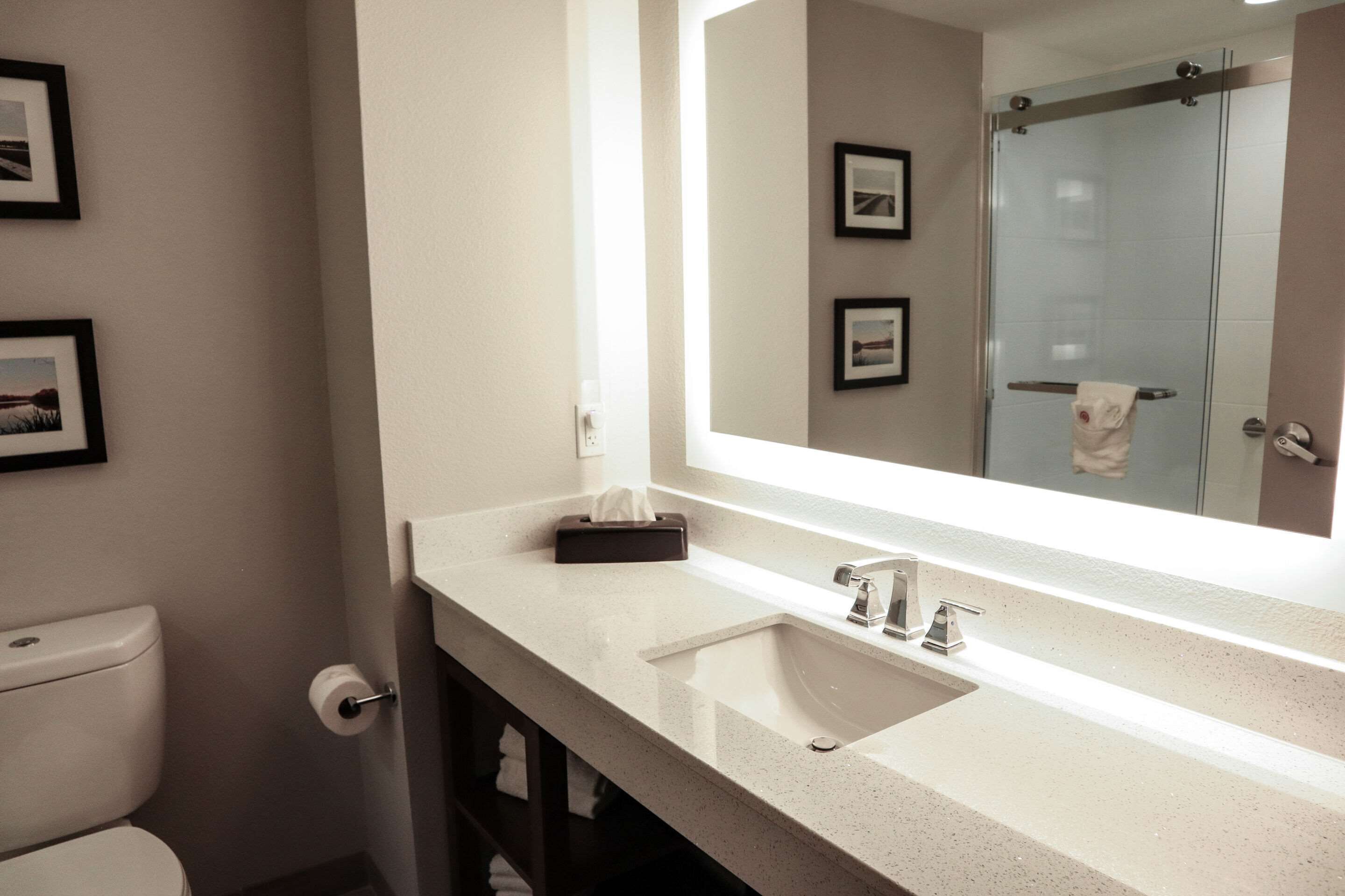 Ein modernes Badezimmer mit einem weißen Waschbecken, einem großen Spiegel und einer Duschkabine aus Glas.