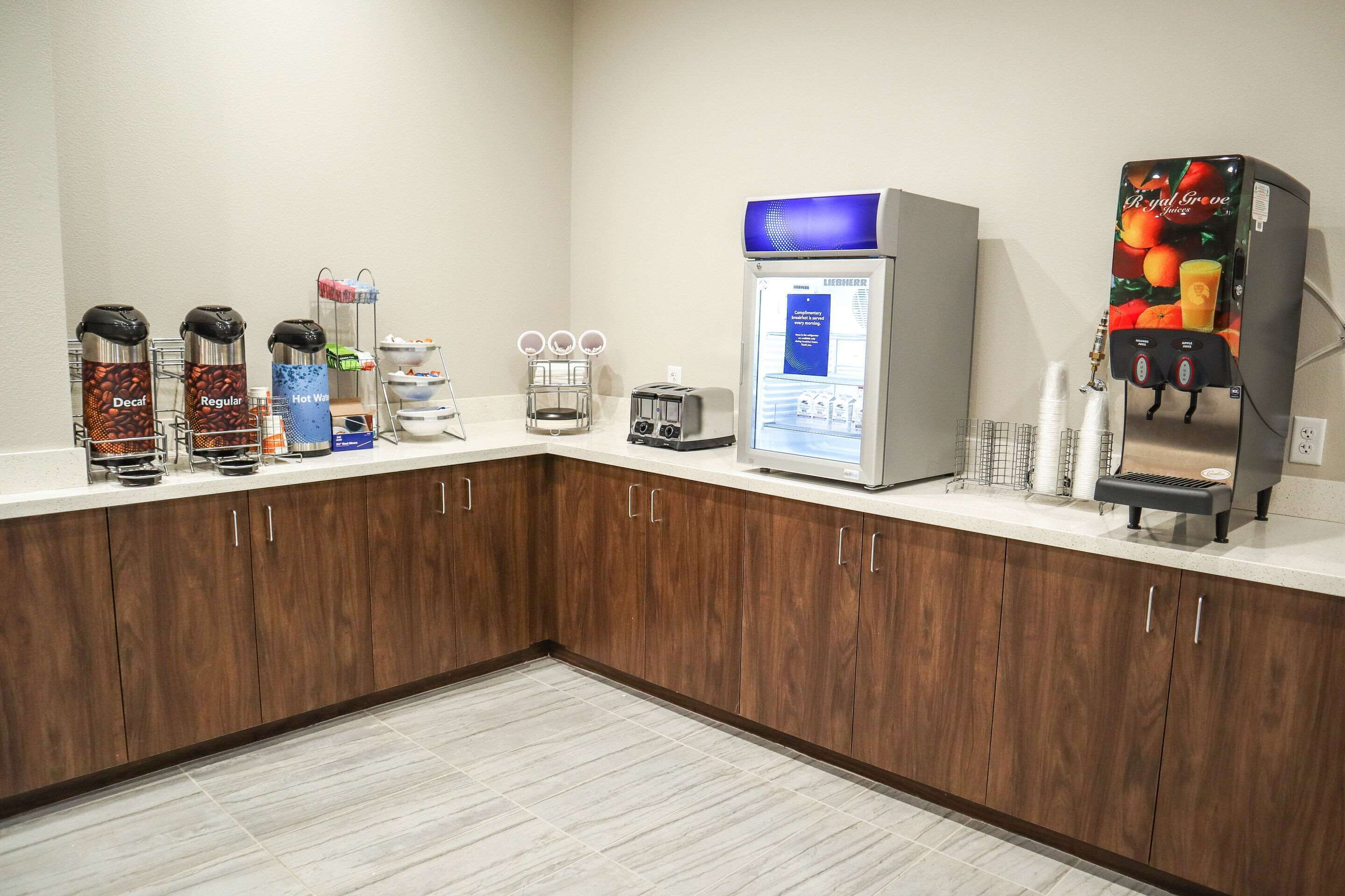 A kitchenette with coffee dispensers, a water cooler, a toaster, and a fruit juice dispenser.