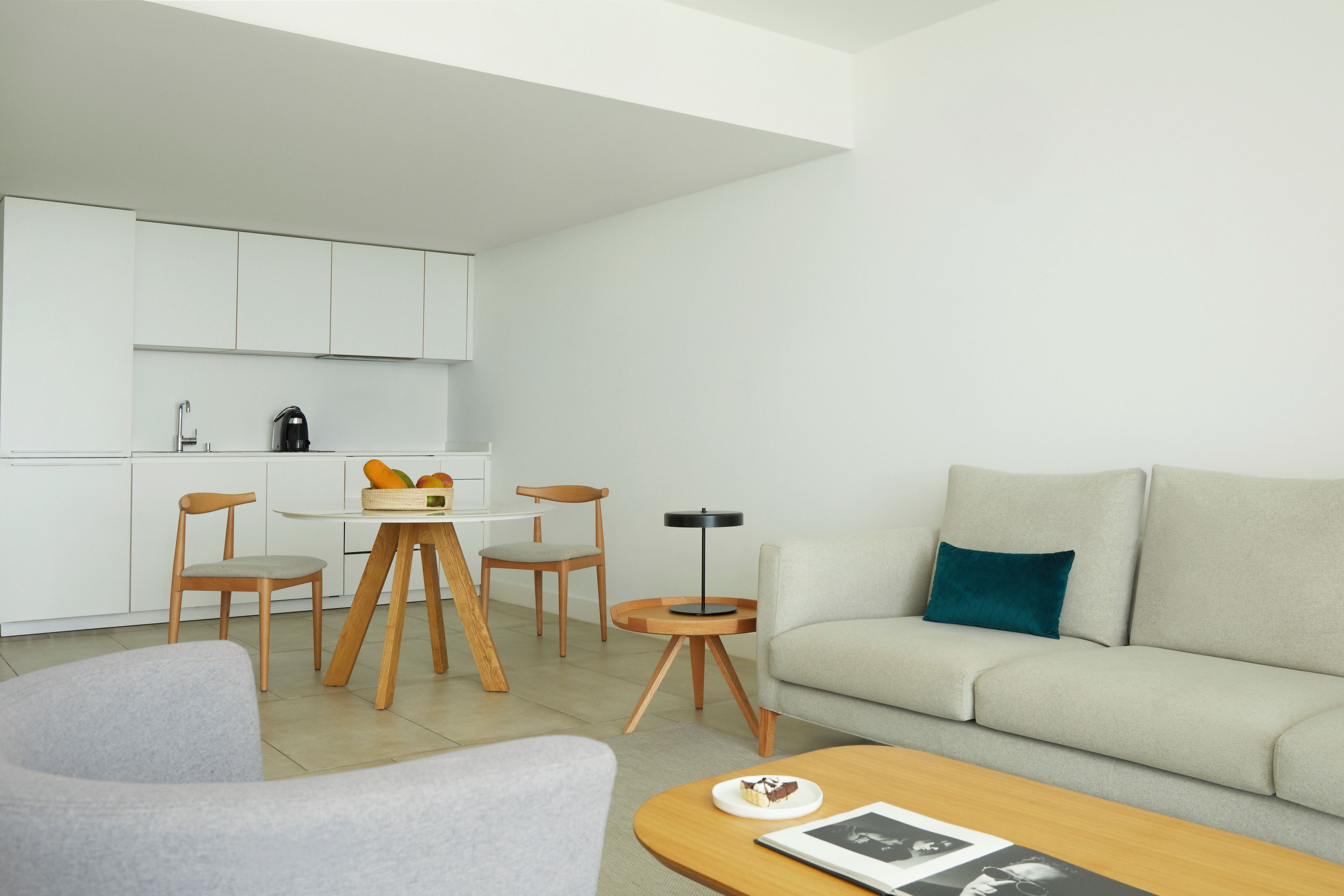 A modern living room with a sofa, a coffee table, and a dining area with chairs and a table.