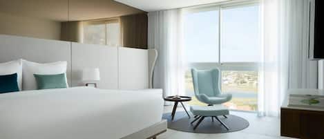 Habitación de hotel moderna con una cama grande, un escritorio, una silla y vistas a la ciudad.