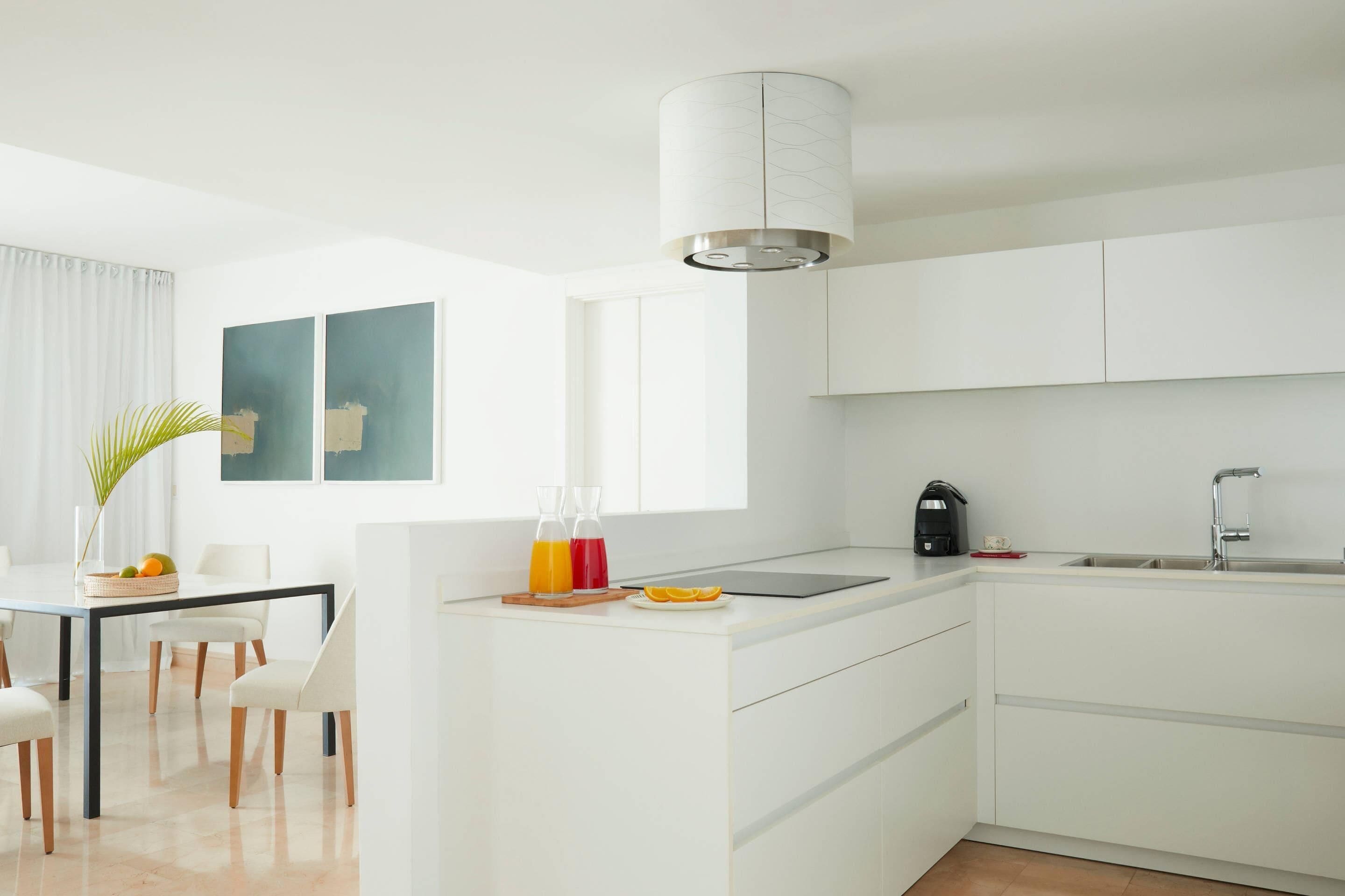 A modern kitchen with white cabinetry, a central island, a built-in sink, and a pendant light.