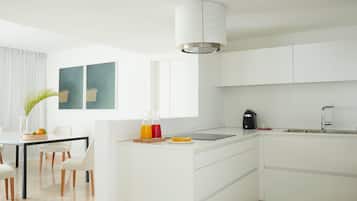 A modern kitchen with white cabinetry, a central island, a built-in sink, and a pendant light.