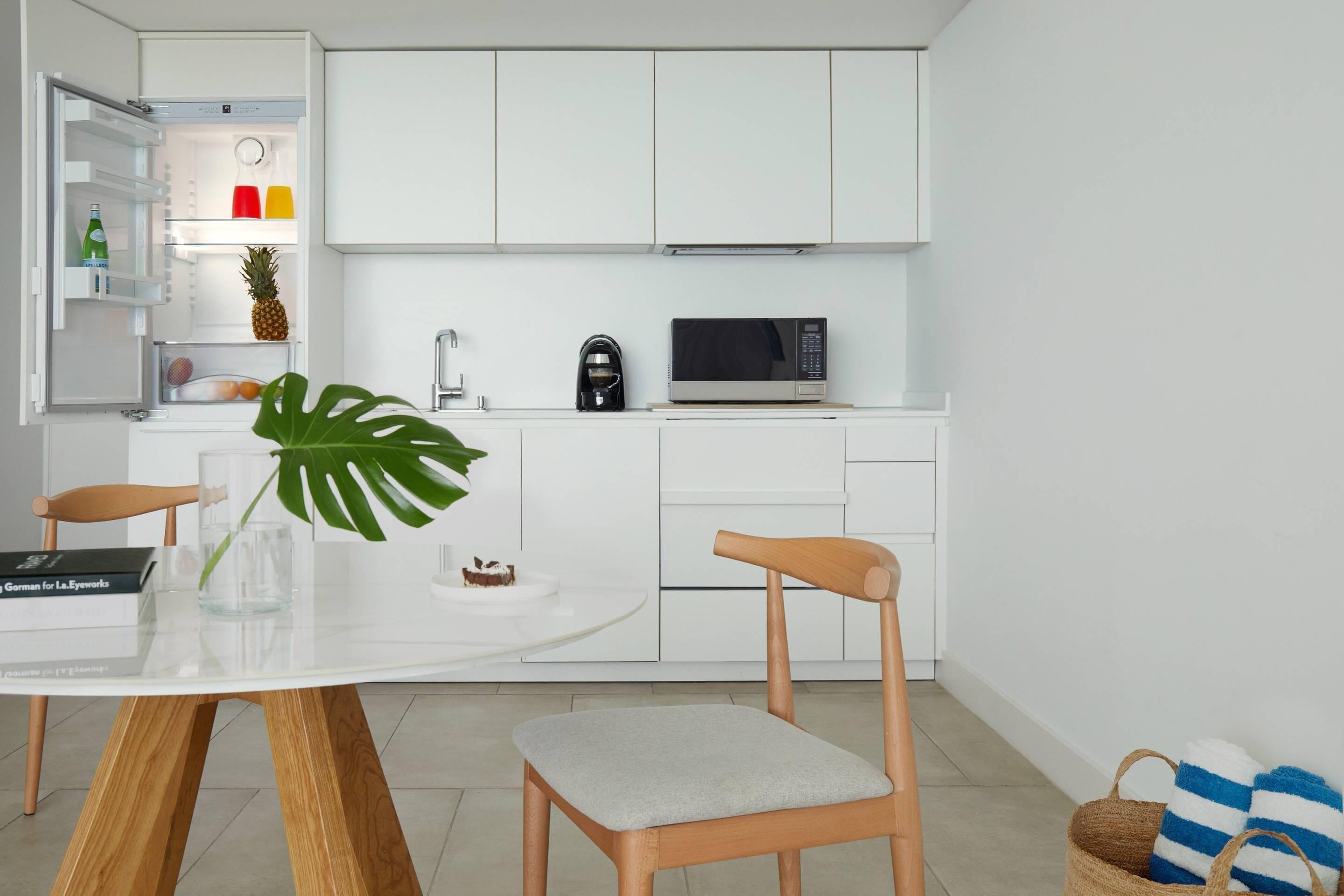 Une cuisine moderne avec des meubles blancs, un four à micro-ondes et un coin repas comprenant une table et des chaises.