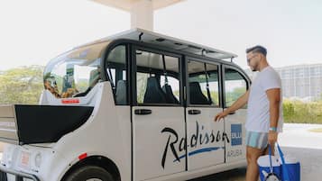 A white Radisson Blu Aruba vehicle with a side door and a roof rack.