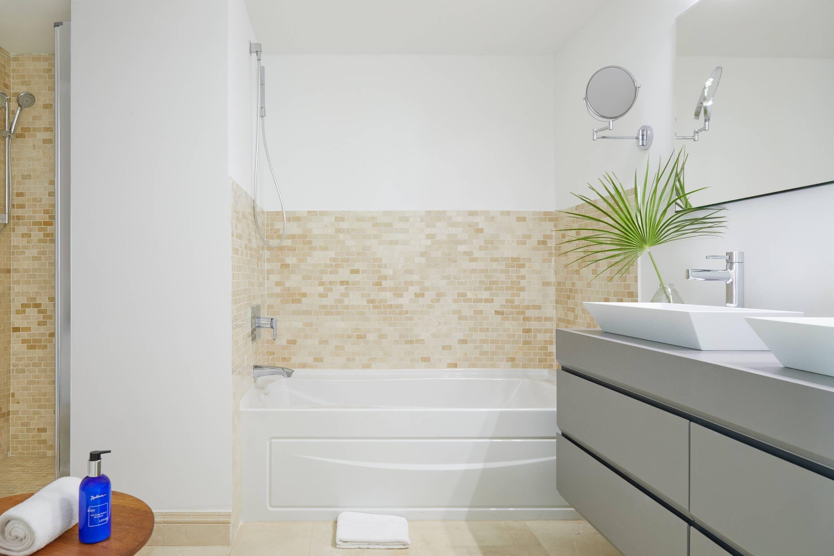 A modern bathroom with a bathtub, a vanity with a sink, and a mirror.