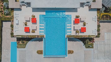 An aerial view of a hotel with a central swimming pool, multiple lounge areas, and a landscaped garden.