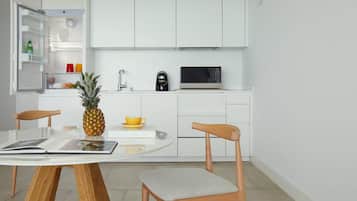 A modern kitchen with white cabinets, a microwave, a coffee maker, and a dining table with chairs.