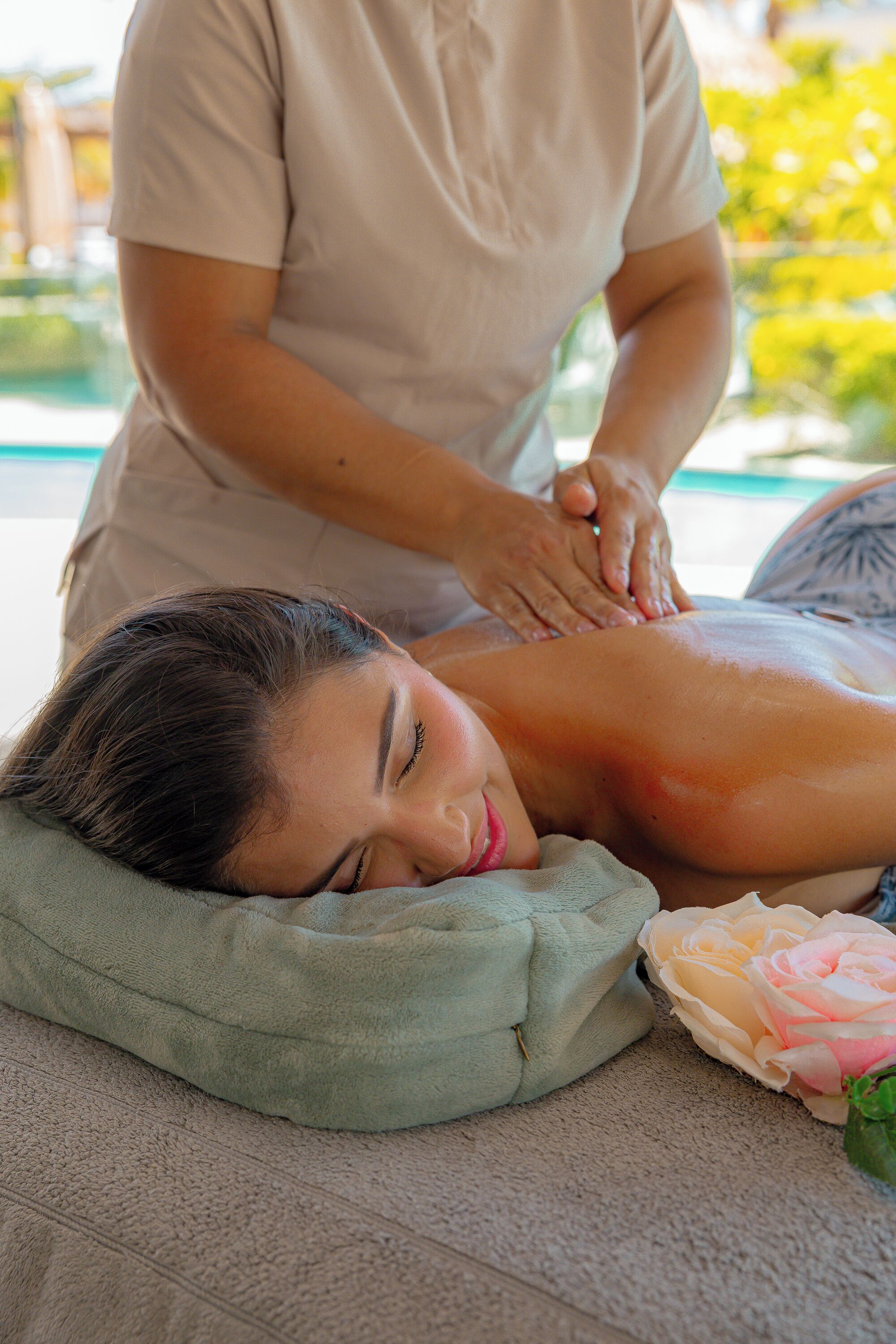 A person receiving a massage in a room with a green pillow and a rose.