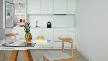 Una cocina moderna con armarios blancos, una cafetera y una mesa de comedor con sillas.