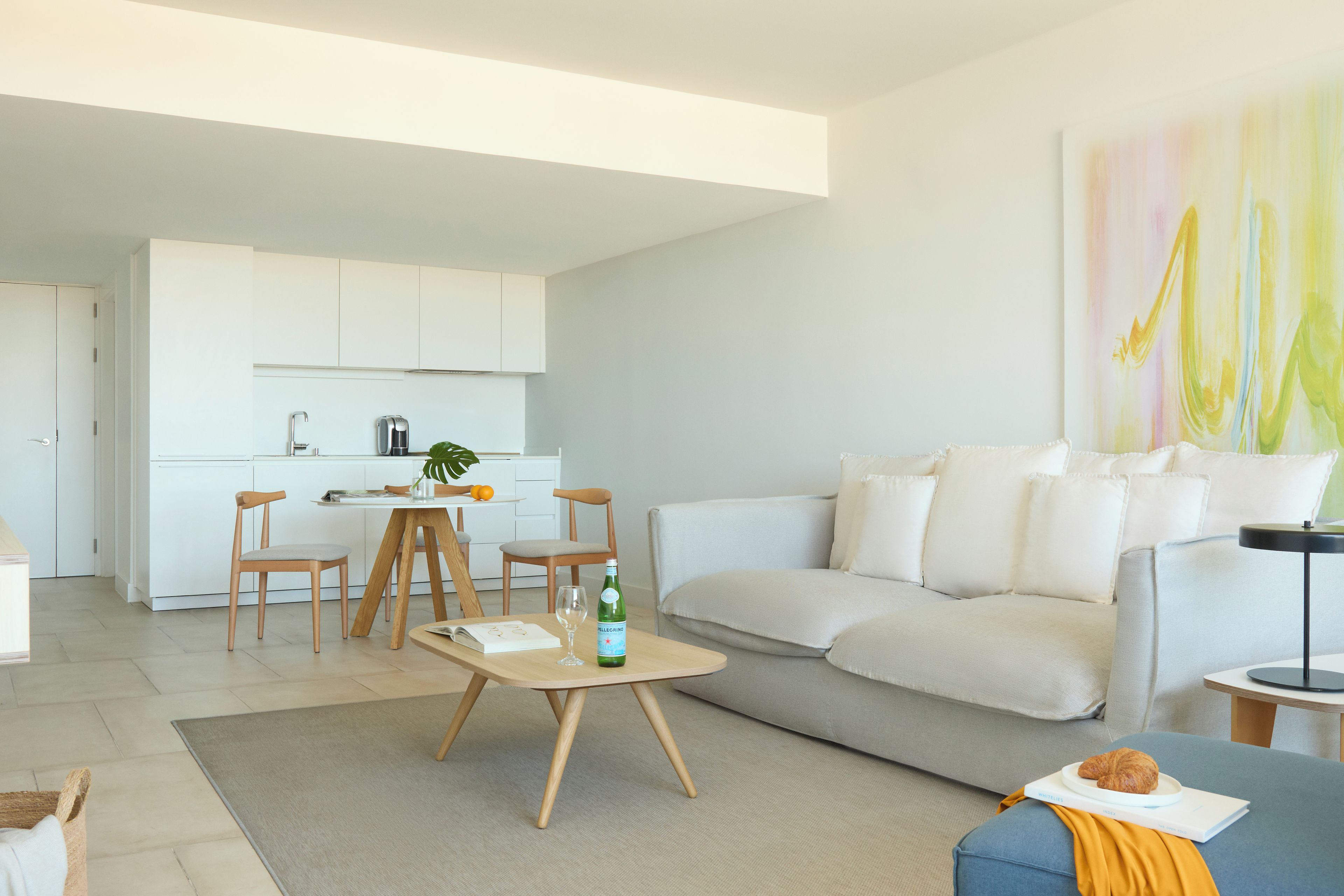 Un salon moderne avec un canapé gris, une table basse et un coin repas comprenant des chaises et une table.