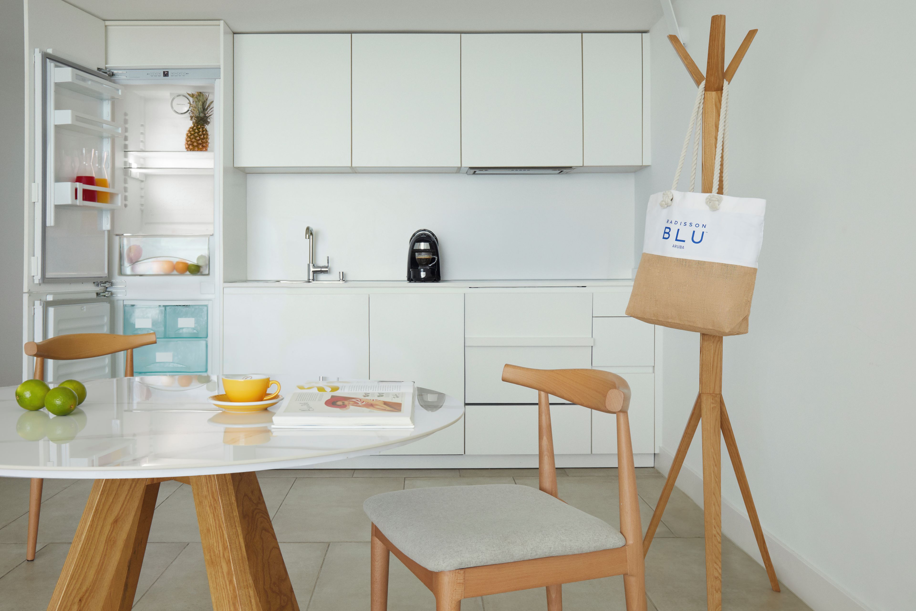 Eine moderne Küche mit weißen Schränken, einer Kaffeemaschine und einem Esstisch mit Stühlen.