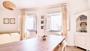 Un comedor moderno con una mesa de madera, sillas blancas y un mueble blanco decorado con objetos.