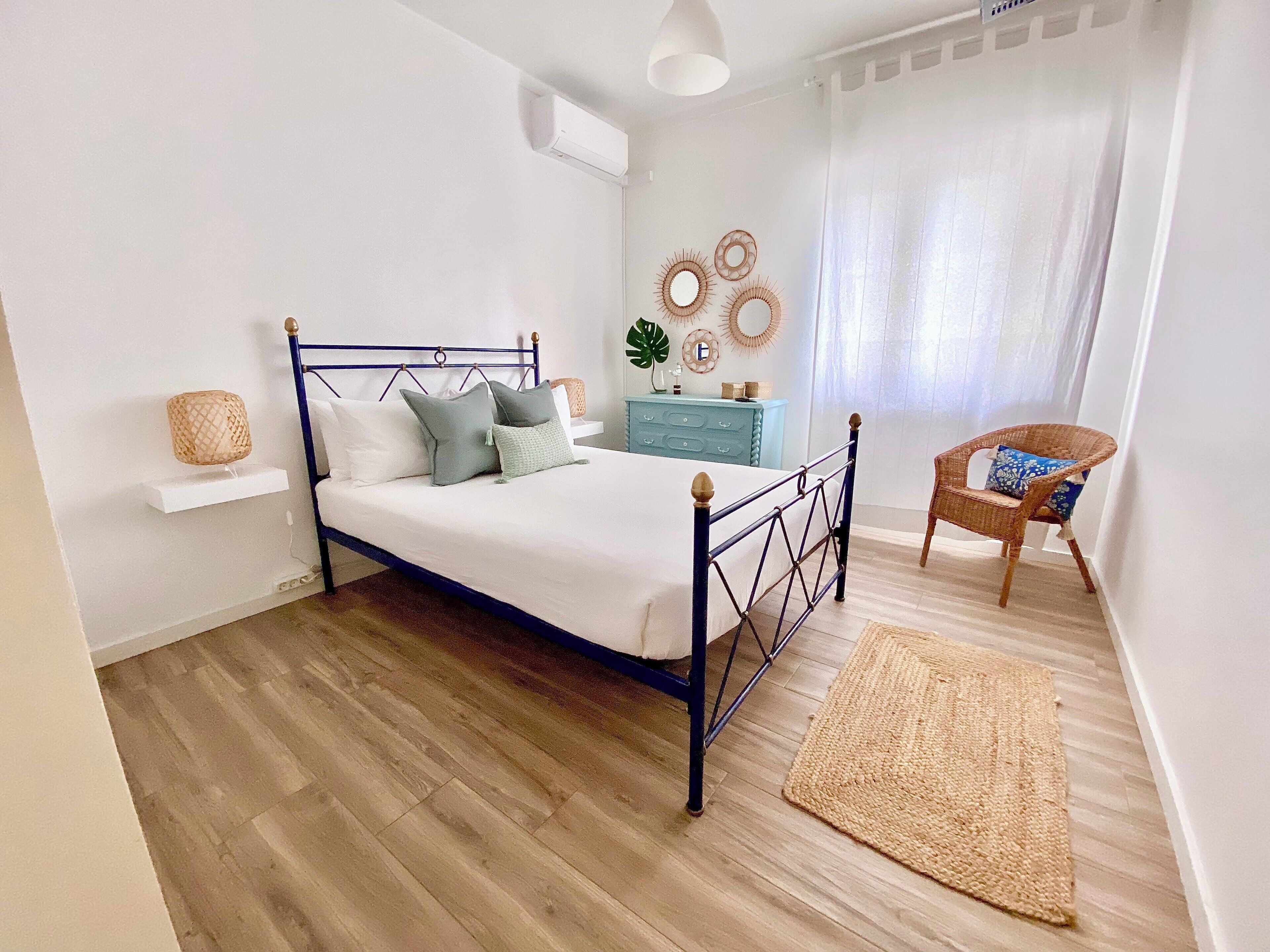 Une chambre à coucher avec un lit, une commode, une chaise et une fenêtre avec des rideaux.